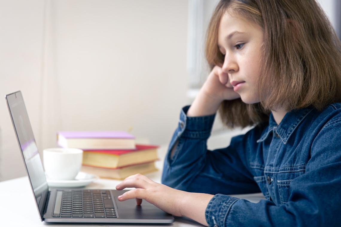 Teen girl sits in front of a laptop, online learning.