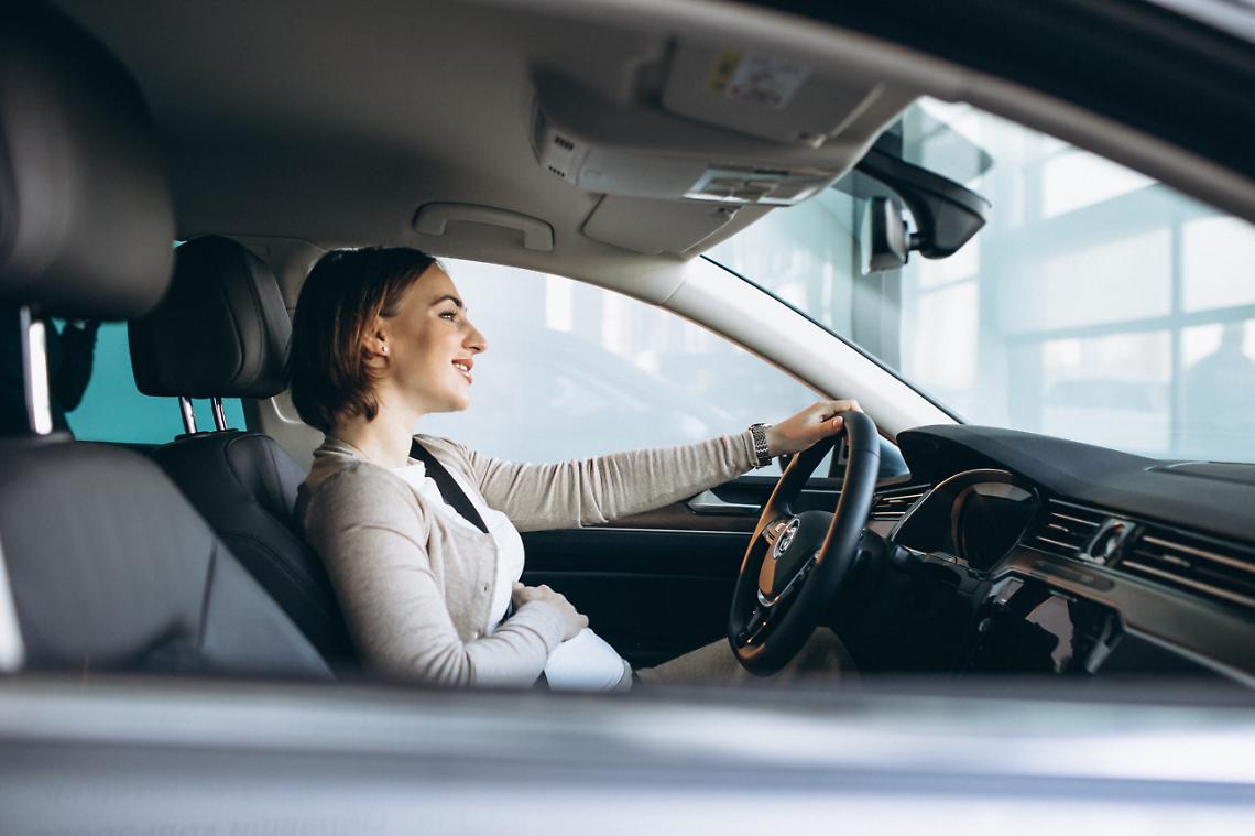 Beautiful pregnant woman driving in car