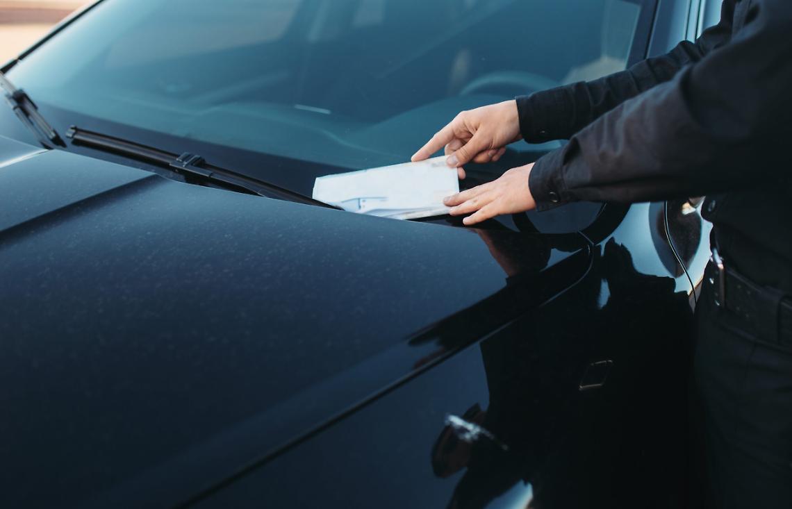 Male policeman in uniform writes a fine on road