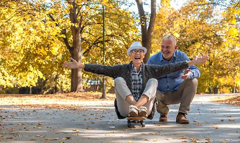 Elderly couple with a woman sitting on skate in the park
