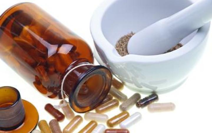 herbs, mortar, pestle and a bottle of capsules