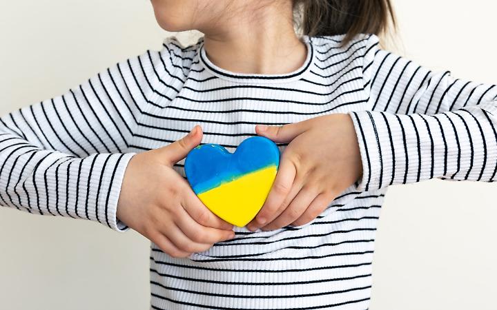 Heart painted in the colors of the flag of Ukraine in children's hands.